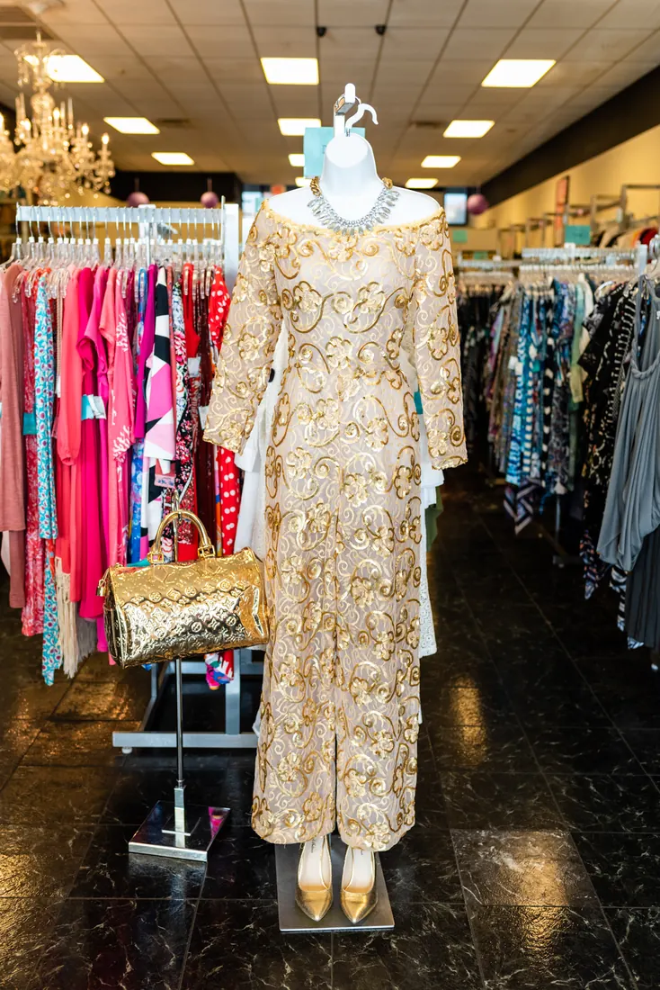 A gold sequined gown on a mannequin at the front of the boutique